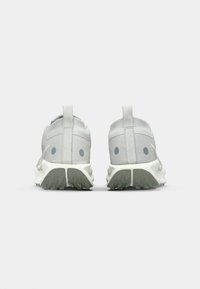 Light gray athletic shoes featuring a textured upper, rounded rear, and strategic rubber soles with traction patterns.