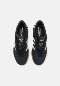 Svarta atletiska sneakers med vita ränder, ovandel i mocka och mesh, gummisula, vadderad krage, symmetrisk snörning och logotyp på tungan.