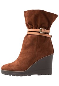 Bruna mockakängor med kilklack och en sladdrig topp, med ett rem av tan läder och en strukturerad mörk gummisula.