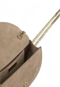 Bolso bandolera de ante beige claro con forma redonda, cadena en tono dorado, cierre de imán y compartimentos interiores.