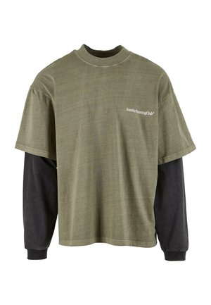 T-shirt verde oliva a maniche corte sovrapposto a una maglietta nera lunga. Presenta un collo rotondo e il testo bianco "Sunday Running Club" sul petto.