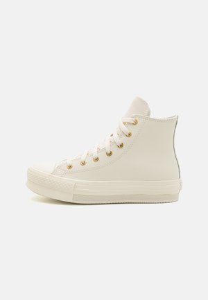 Højtop hvid sneaker med hvide snørebånd, guldfarvede metaløje, gummisål og tekstureret tåkap, vist fra siden.