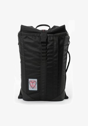 Sac à dos noir en tissu résistant, doté d'un rabat supérieur, de coutures renforcées et d'un insigne avec un symbole de paix. Design minimaliste.