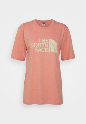 Jasnoróżowa (koralowa) koszulka z krótkim rękawem i okrągłym dekoltem, z logo "THE NORTH FACE" i grafiką półkopuły w bladym żółtym kolorze na środku przodu.