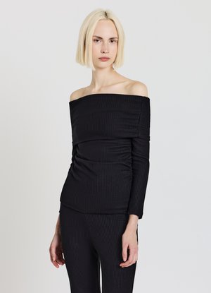 Top nero a coste scivolato sulle spalle con maniche lunghe, caratterizzato da una texture raccolta e un design aderente, abbinato a pantaloni coordinati a coste.