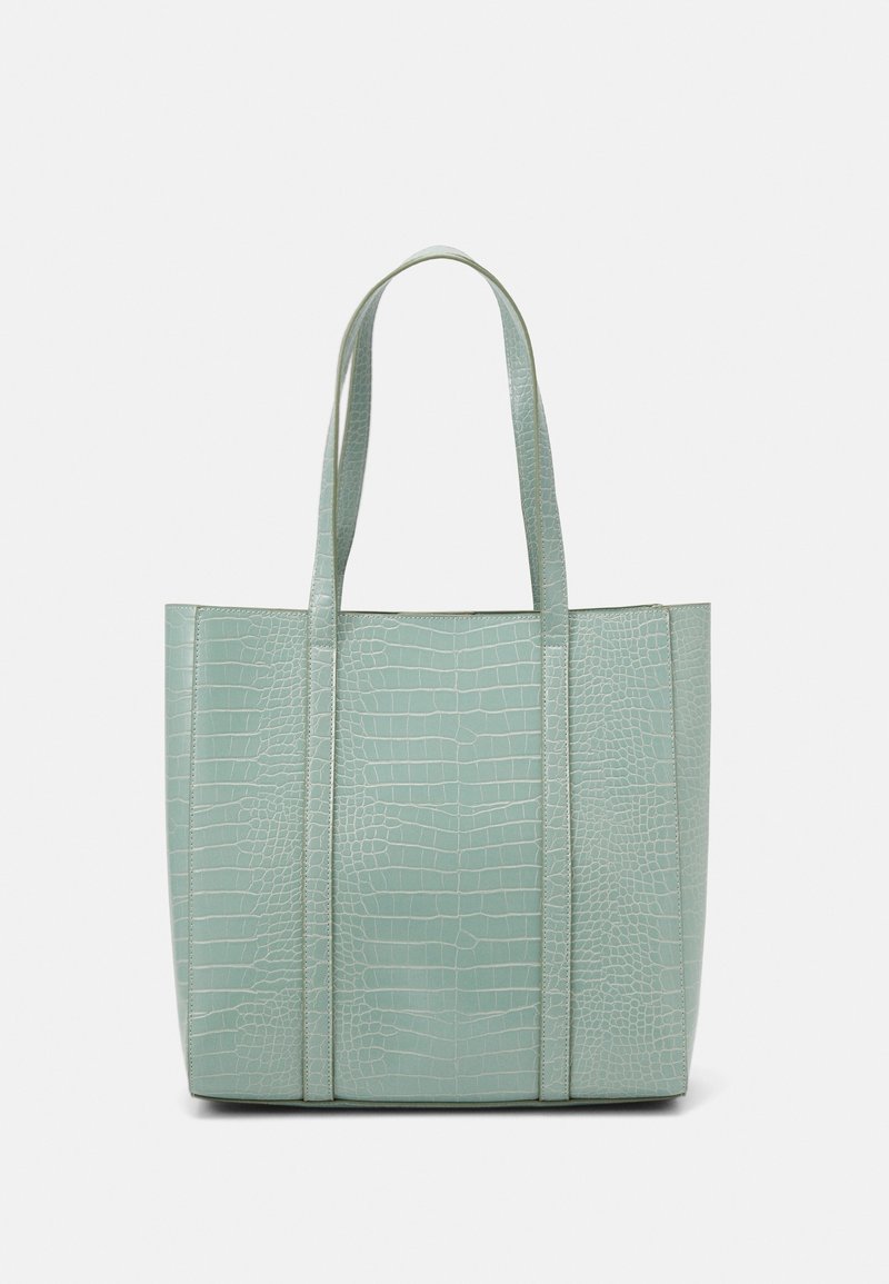 Sac cabas vert clair avec texture crocodile et deux longues anses sur fond blanc uni.