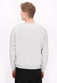 Pulover gri cu guler rotund și mâneci lungi, fabricat dintr-un material moale, având manșete și un tiv cu nervuri. Design simplu, fără modele vizibile.