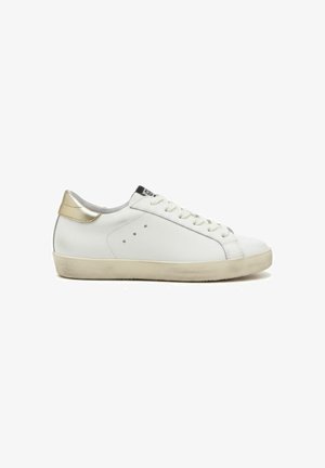 Witte lage sneaker met beige zool en gouden hieltab, uitgevoerd met veters aan de voorkant en kleine ventilatiegaatjes aan de zijkant.