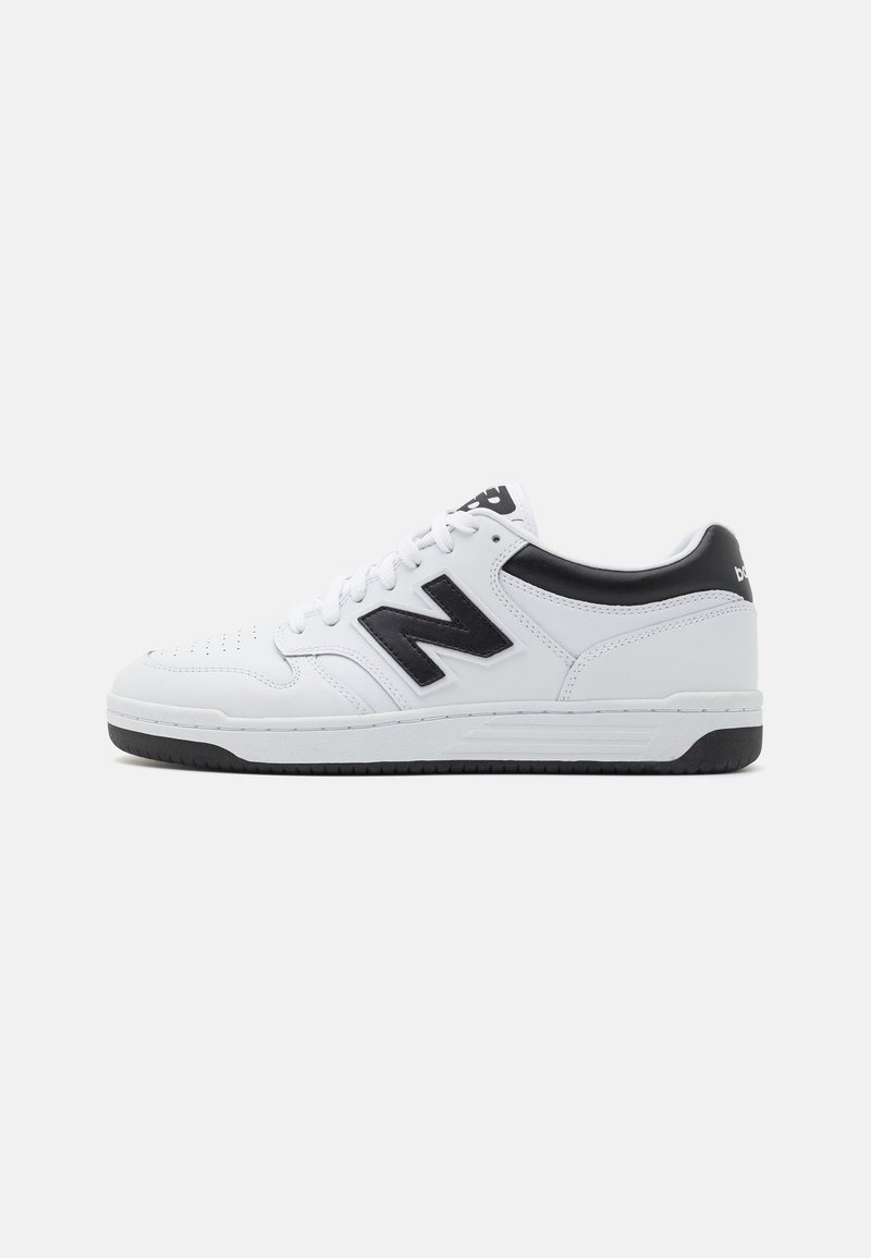 Weiße Sportschuhe mit schwarzen Akzenten. Eigenschaften sind ein glattes Leder-Upper, eine perforierte Zehenpartie, ein auffälliges Logo und eine flache schwarze Gummisohle.