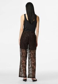 Black tank top paired with brown lace pants featuring floral patterns and a sheer design. Elastic waistband; smooth texture with intricate detailing.