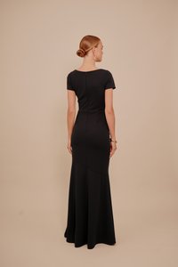 Czarna sukienka do podłogi z dopasowanym górnym fasonem, krótkimi rękawami i sylwetką syrenki. Posiada gł�ęboki dekolt na plecach oraz przeszycia modelujące.