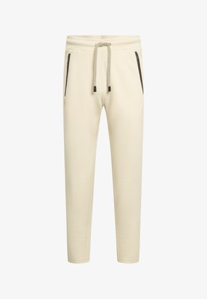 Sahnefarbene, schmal zulaufende Jogginghose mit Kordelzug an der Taille und schwarzen Reißverschlusstaschen auf beiden Seiten.