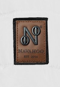 Brown leather label with black embossed logo "N" and "NAVAHOO EST 2014" on white fabric background, bordered with dark gray felt.
