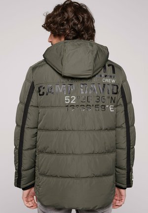 Chaquetón acolchado verde oliva con capucha, que cuenta con acentos en negro, texto en relieve en la espalda y una textura acolchada.