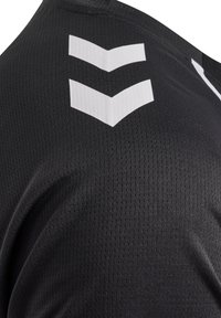 Maillot de sport noir en tissu texturé. Présente un design d'accent en chevron blanc sur l'épaule. Matériau léger et respirant.