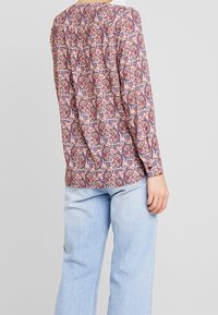 Langærmet bluse i paisley-mønster med nuancer af pink, blå og krem. Har en løst fit, samlet ryg og knaplukning ved ærmerne.