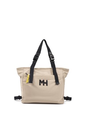 Bolso tote beige con correas negras ajustables para el hombro, bolsillo delantero con cremallera y pestaña amarilla, y logo negro "MH" en el frente.