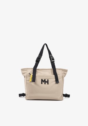 Bolso tote beige con correas negras ajustables para el hombro, bolsillo delantero con cremallera y pestaña amarilla, y logo negro "MH" en el frente.
