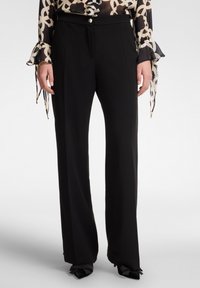 Pantaloni neri a gamba larga con una vestibilità su misura, realizzati in un tessuto morbido, con pieghe frontali e chiusura a pulsante.