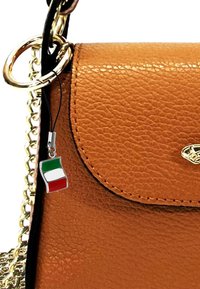 Bruine nep-lederen handtas met een gouden kettingriem, een ronde flap en een charm met de kleuren van de Italiaanse vlag. Textuurdetails zijn zichtbaar.