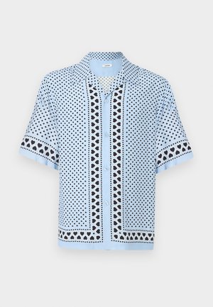 Chemise bleu clair à manches courtes avec motif de cœurs noirs et blancs sur l'ensemble du tissu ainsi que sur les bordures des manches et du devant.