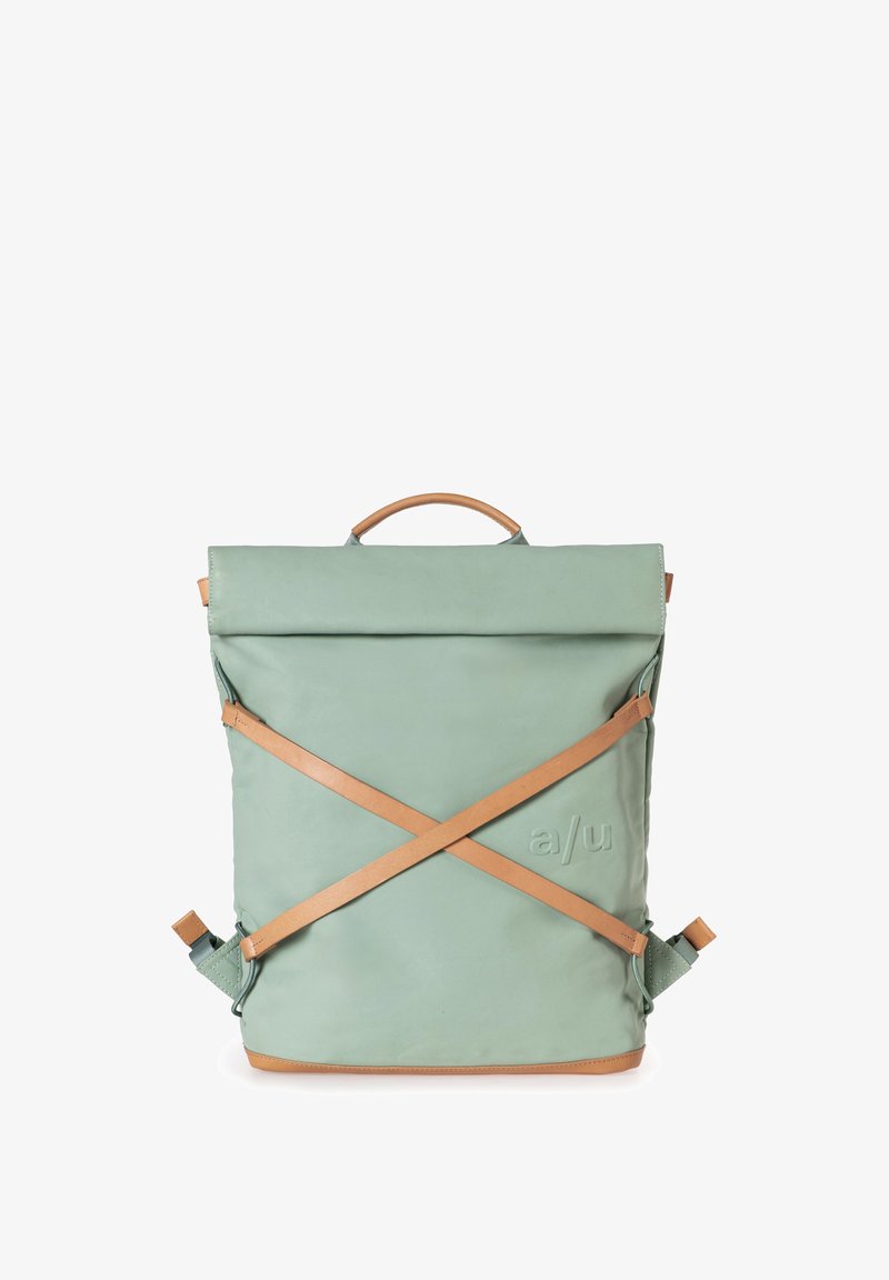 Zaino verde a roll-top con una superficie texturizzata, dotato di spallacci e dettagli in pelle marrone, una maniglia superiore e un dettaglio logo opaco.