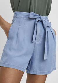 Light blue short trousers made of soft fabric, featuring a tie belt at the waist, pleats, and side pockets.