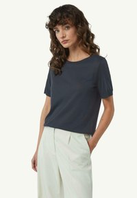 Czarna krótka koszulka z okrągłym dekoltem, wykonana z miękkiego materiału, zestawiona z jasnymi spodniami o wysokim stanie.