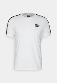 T-shirt blanc en coton avec col rond, manches courtes, accents de rayures noires sur les épaules et un petit logo EA7 sur la poitrine.