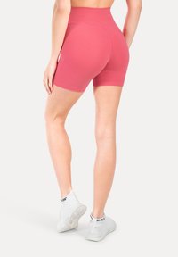 Różowe szorty z wysokim stanem w dopasowanym kroju, wykonane z elastycznego materiału. Charakteryzują się gładką teksturą i minimalnymi detalami szwów.