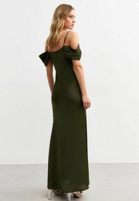 Olivgrön, off-shoulder kvällsklänning med puffärmar, figurnära silhuett och golvlång design. Har tunna axelband.