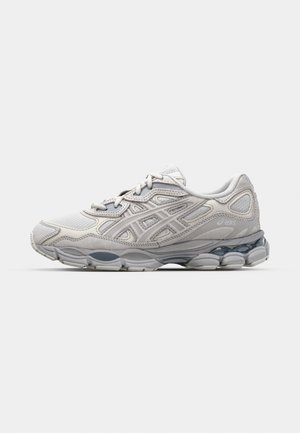 Zapatilla deportiva gris con parte superior de malla y superposiciones sintéticas, que cuenta con una suela acolchada y acentos texturizados en los laterales.