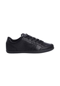Zapatillas negras con parte superior de cuero suave, acentos texturizados, cordones planos y suela de goma de perfil bajo. Presenta una costura lateral decorativa.