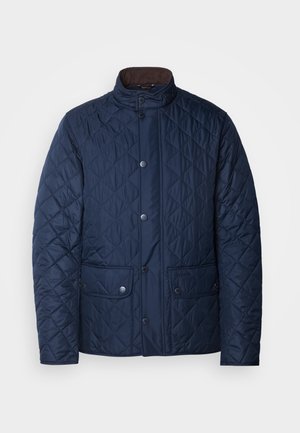 Navy quilted jacket with a high collar, snap button closure, two front pockets, and a textured diamond pattern.