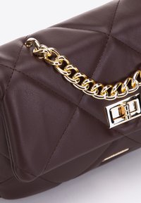 Brązowa torebka skórzana pikowana z złotym łańcuszkiem i prostokątnym zapięciem. Gładka faktura i wyraźny kształt.