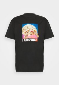 Camiseta de algodón negra con un gráfico colorido de una tortuga con gafas de sol, rodeada de un fondo galáctico, con el texto "SOY VELOCIDAD."