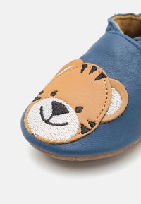 Scarpe in pelle per bambini di colore blu e beige con un design a faccia di tigre sulla punta. Presentano dettagli ricamati e una suola morbida.