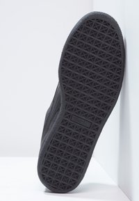 Semelle de chaussure de sport noire avec un motif géométrique texturé. Fabriquée en caoutchouc, présentant un logo et un bord lisse le long du contour.