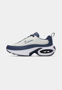 Nike tenisice s bijelim gornjim dijelom i tamnoplavim naglascima, koje imaju valoviti dizajn, teksturiranu tkaninu i vidljivu jedinicu zračne amortizacije.
