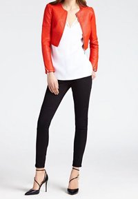 Rode gebreide leren jas, witte blouse, zwarte slim-fit broek en zwarte stilettohakken met enkelbandjes voor een strak, modern uiterlijk.