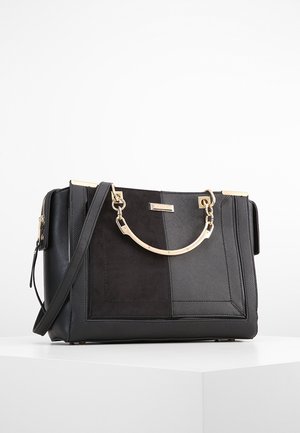 Sac à main structuré noir avec poignée en métal doré et bandoulière amovible sur une surface blanche.