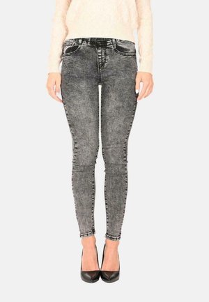 Jeans skinny a righe nere e grigie con tasche frontali e chiusura con bottone, abbinati a scarpe con tacco nere.