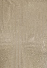 Tissu en maille côtelée texturé de couleur beige clair avec un subtil éclat. La surface présente des lignes verticales et un design ajusté.
