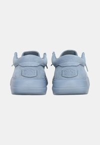 Sneaker in suede bluastro, con collo imbottito, suola in gomma e logo impresso sul tallone. Texture liscia, forma arrotondata, vista dal retro.