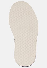 Bílá gumová podešev boty s texturovaným povrchem a kruhovými vzory, se zakřiveným, zaobleným okrajem.