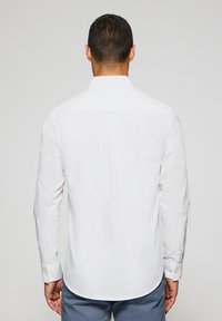 Witte overhemden met lange mouwen, voorzien van een rugdeel en knoopmanchetten, gemaakt van soepel katoen, met een afgeronde zoom en subtiele stikdetails.