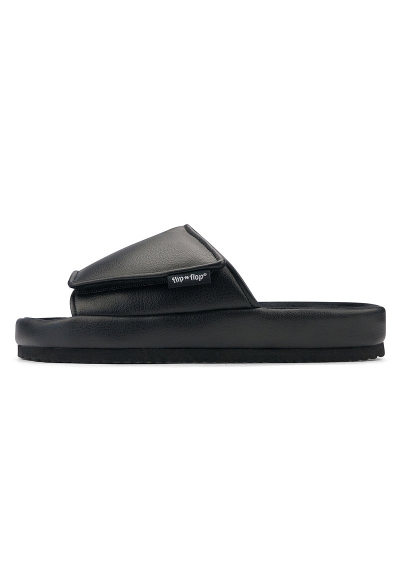 Black slide sandals with a padded upper and a textured sole, featuring a flap design and a small brand logo tag on the side.