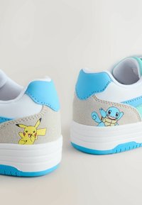 Modre in bele superge s teksturiranim svetlo sivim semišem na peti. Na zunanji strani so prikazani ilustraciji Pikachuja in Squirtla.