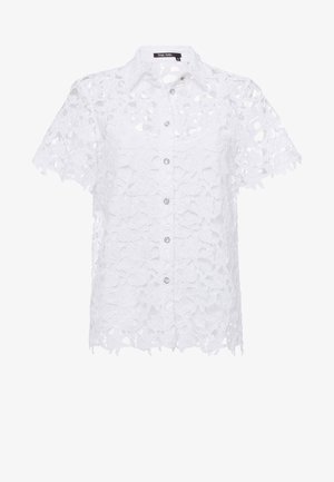 Blouse blanche à manches courtes avec boutons, motif en dentelle florale et col, dotée d'un design semi-transparent et d'une étiquette de marque à l'intérieur du col.