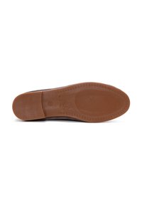 Semelle de chaussure en suède marron avec une surface texturée, présentant une semelle en caoutchouc, des détails de couture et une finition brillante sur le talon.